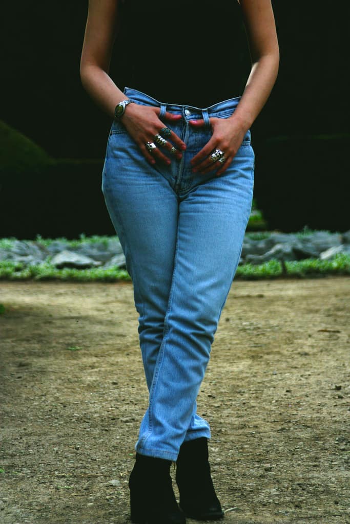 Stylish woman posing outdoors in blue jeans and boots, showcasing modern casual fashion.