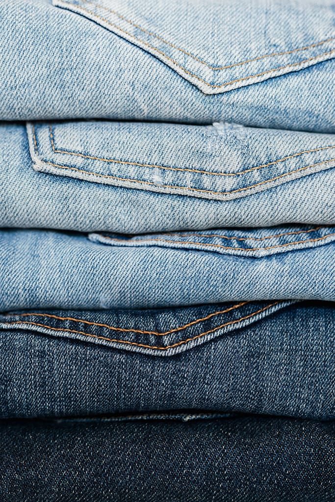 Close-up view of stacked denim jeans showcasing different shades and styles for fashion retail.