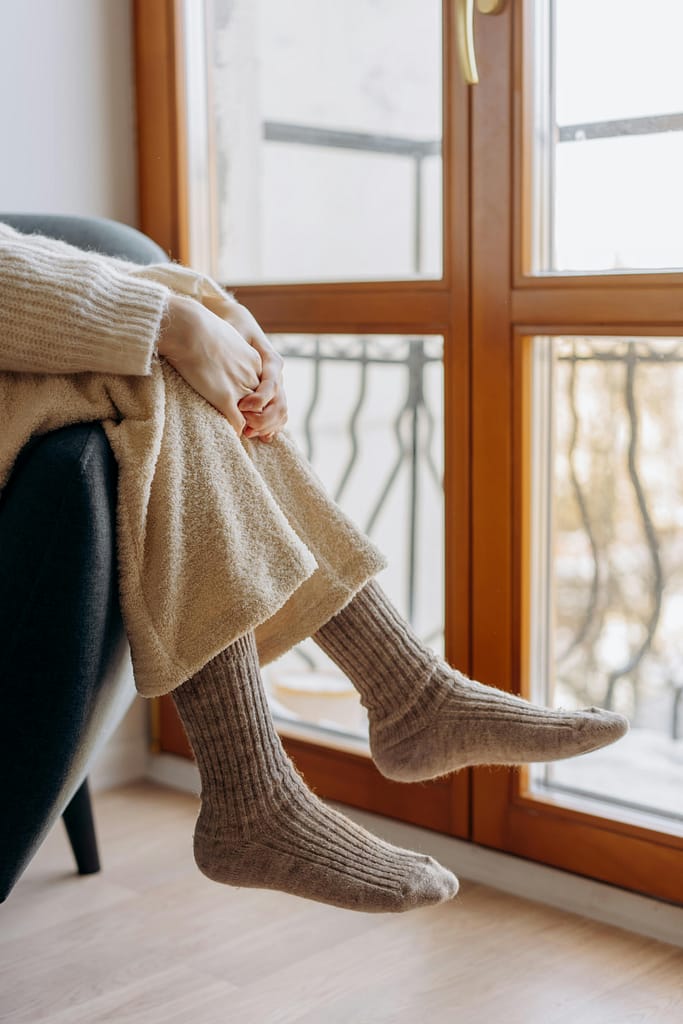 A serene indoor scene of a person relaxing in warm knitwear by a window.