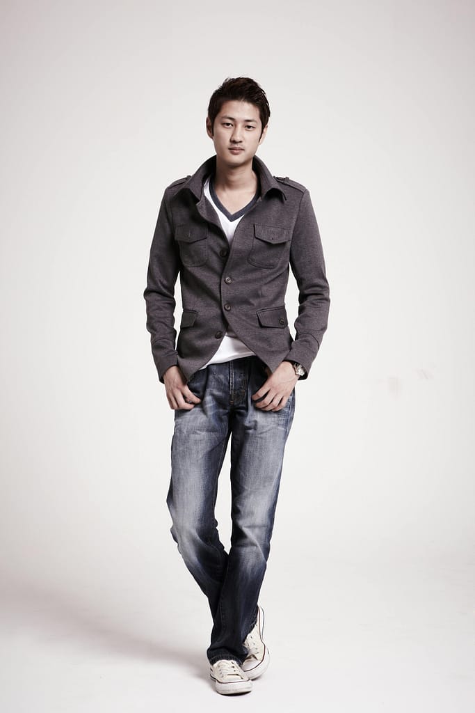 A fashionable young man posing confidently in a studio setting, wearing casual attire.